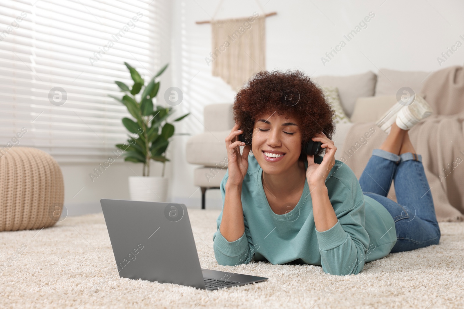 Photo of Beautiful young woman in headphones using laptop in room