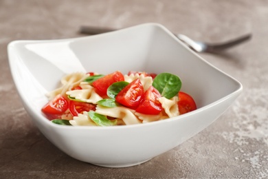 Photo of Bowl with delicious pasta primavera on grey background