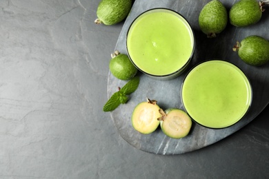 Photo of Fresh feijoa smoothie and fresh fruits on grey table, flat lay. Space for text