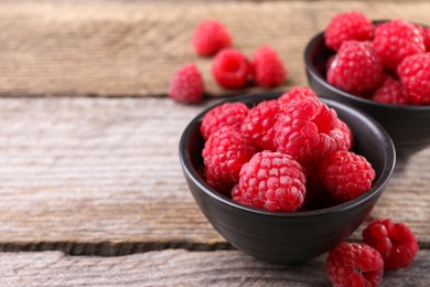 Photo of Tasty ripe raspberries on wooden table, space for text