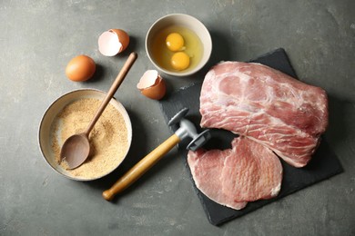 Photo of Raw pork chops and ingredients for cooking schnitzel on grey table, flat lay