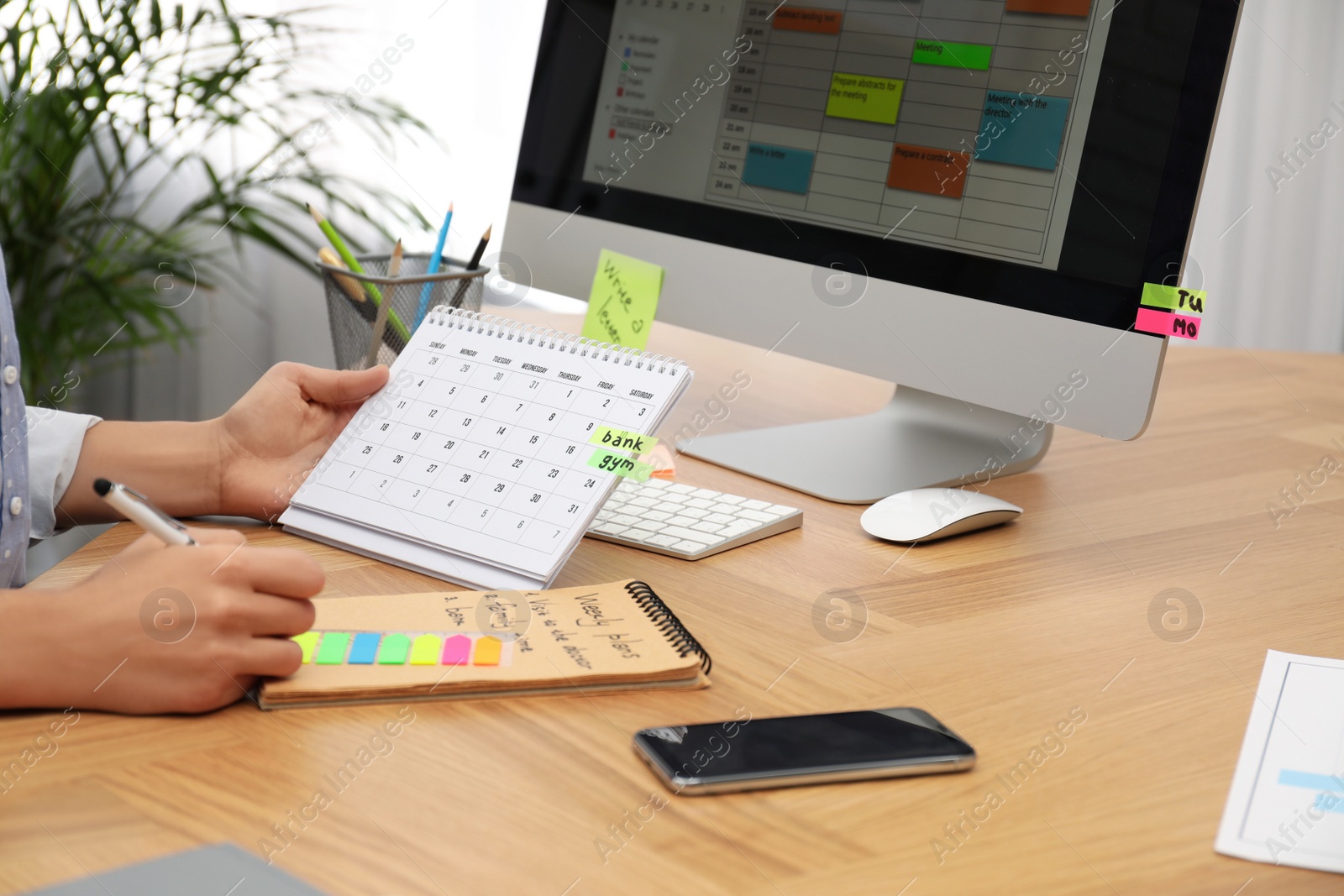 Photo of Woman making schedule using calendar at table in office, closeup