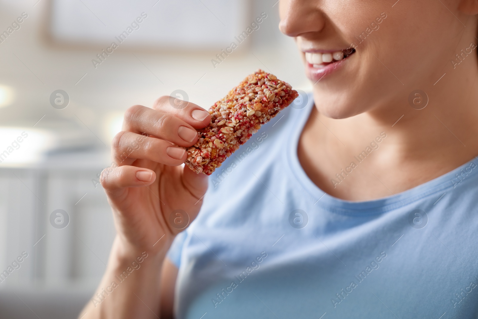 Photo of Woman eating tasty granola bar at home, closeup