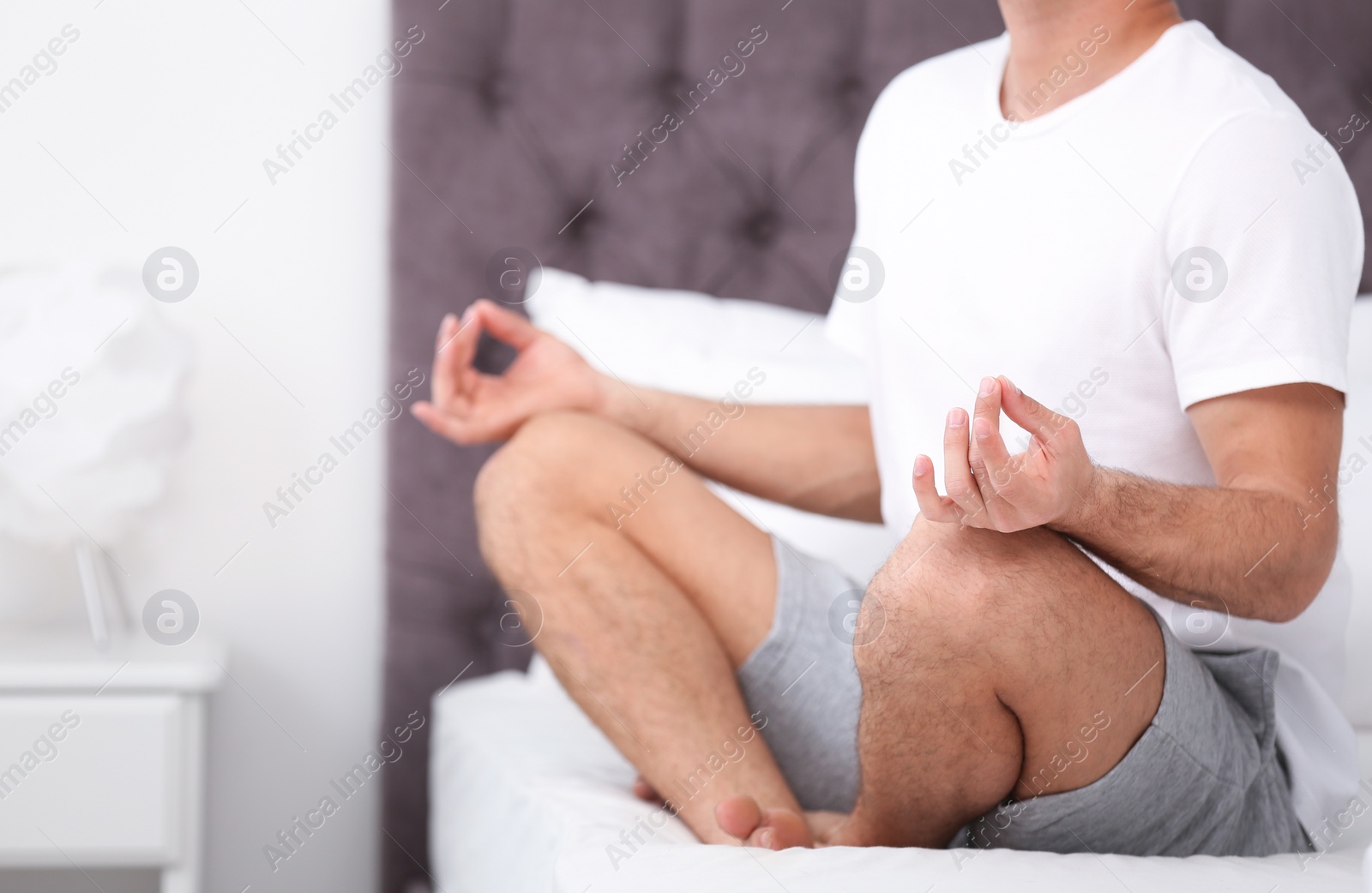 Photo of Man meditating on bed at home, closeup. Zen concept