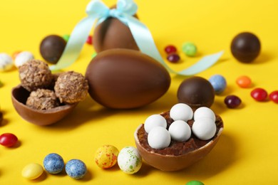 Photo of Tasty chocolate eggs and candies on yellow background
