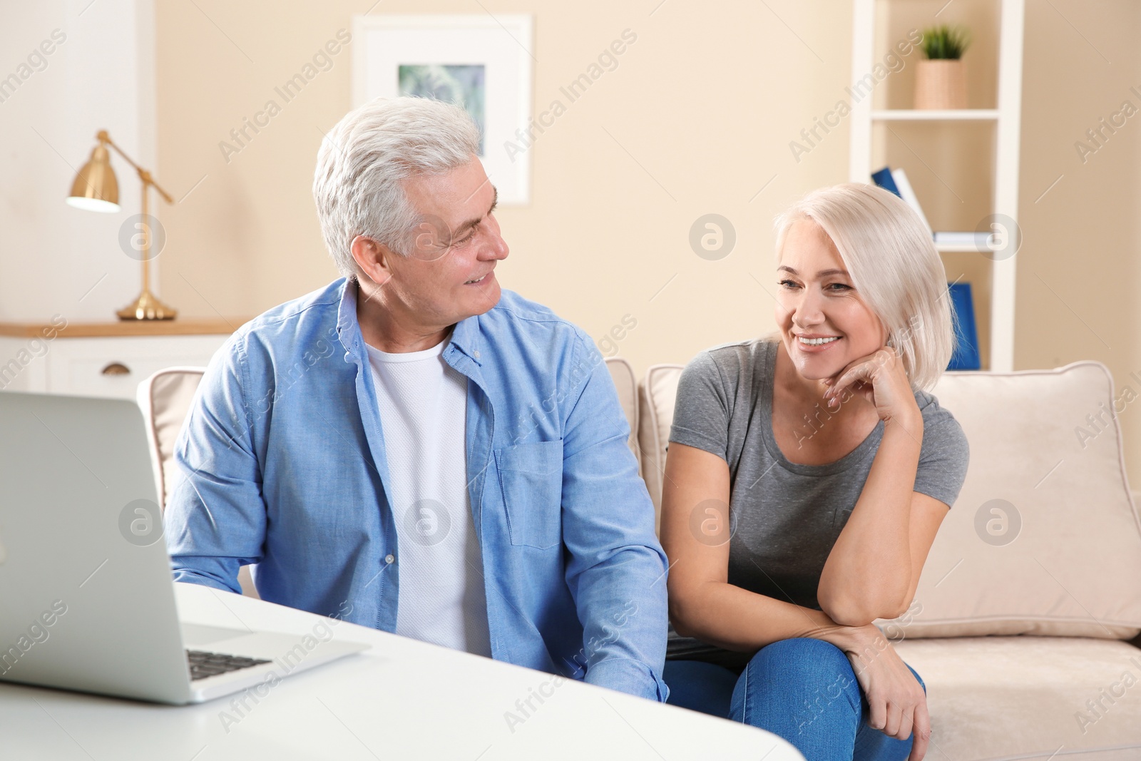 Photo of Mature couple using video chat on laptop at home