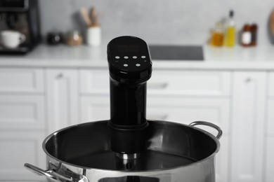 Photo of Pot with sous vide cooker in kitchen, closeup. Thermal immersion circulator