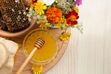Photo of Delicious honey, combs and different flowers on wooden table, top view. Space for text