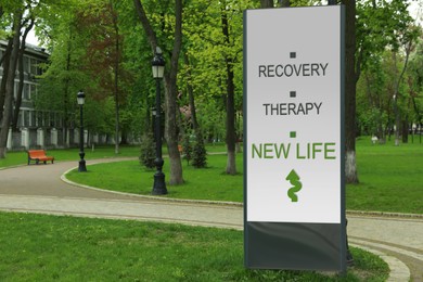 Image of Start to live without alcohol addiction. Advertising board with inscription RECOVERY, THERAPY AND NEW LIFE  in park