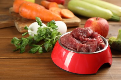 Photo of Raw meat and fresh ingredients on wooden table, closeup. Natural pet food