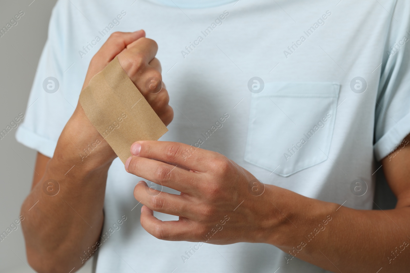 Photo of Man putting sticking plaster onto hand, closeup