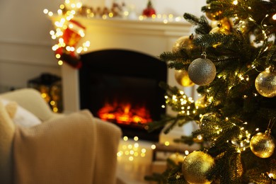 Photo of Beautiful Christmas baubles hanging on fir tree in room, space for text