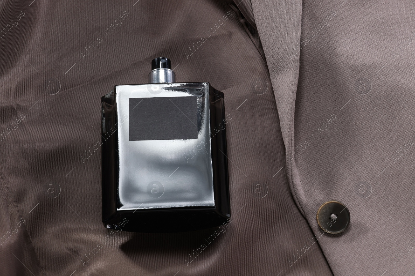 Photo of Luxury men's perfume in bottle on beige jacket, above view. Space for text