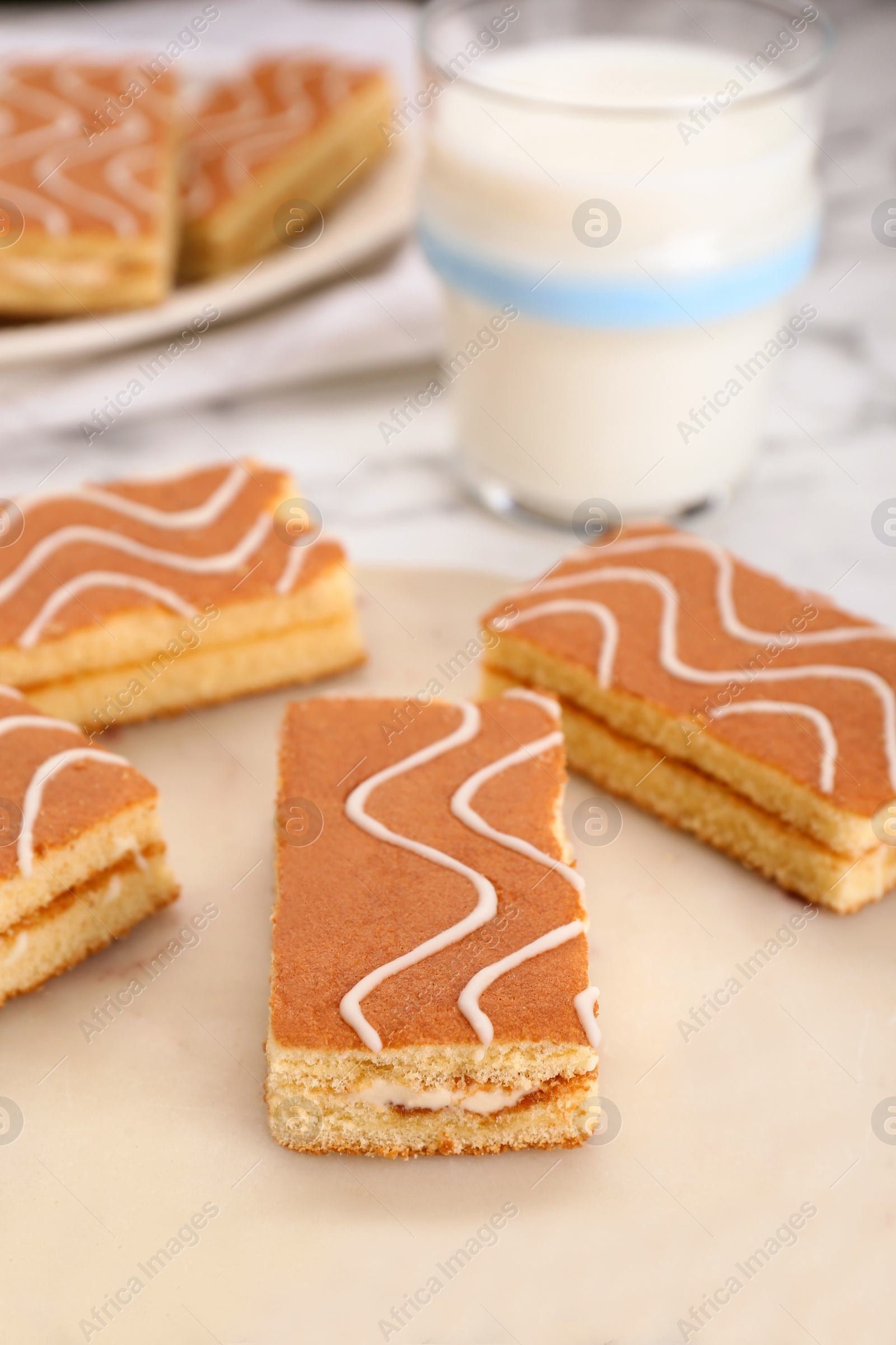 Photo of Tasty sponge cakes and milk on white marble table, closeup