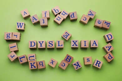 Photo of Wooden cubes with word Dyslexia on light green background, flat lay