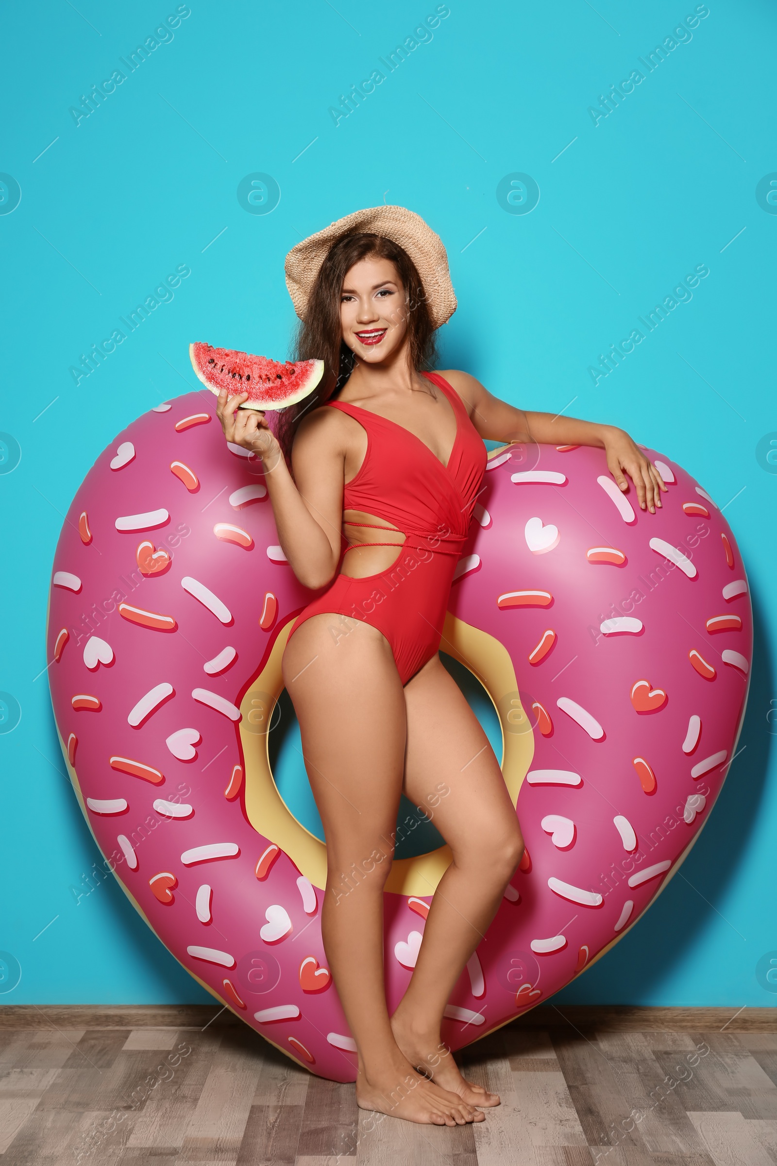 Photo of Beautiful young woman with inflatable heart and watermelon near color wall