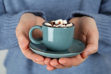 Woman holding cup of delicious hot chocolate with marshmallows and syrup, closeup