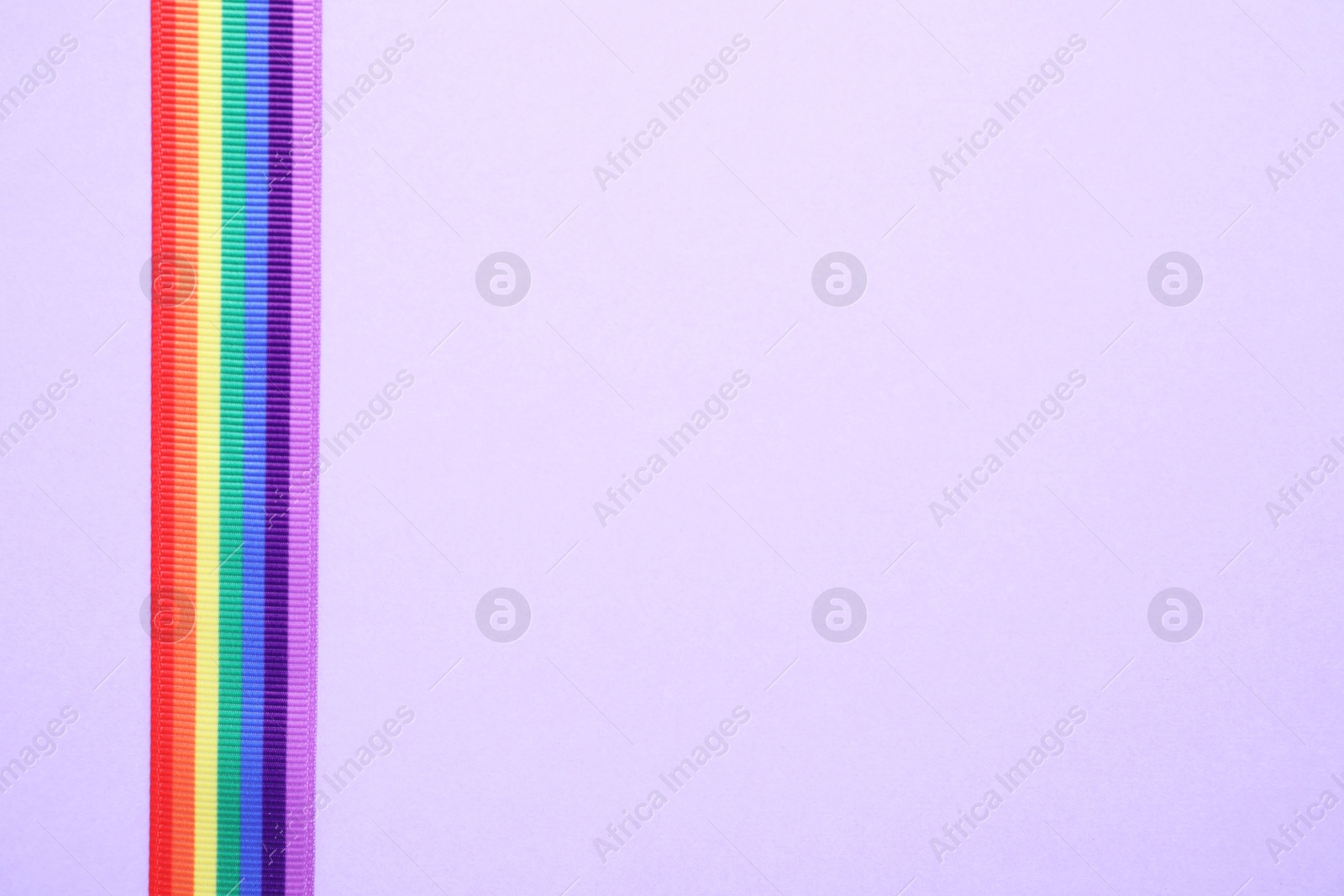 Photo of Bright rainbow ribbon on color background, top view with space for text. Symbol of gay community