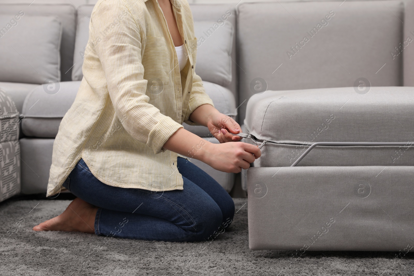 Photo of Woman making sleeping place for guest in living room, closeup. Convertible sofa