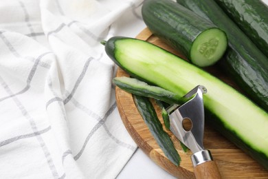 Fresh cucumbers and peeler on table, closeup. Space for text