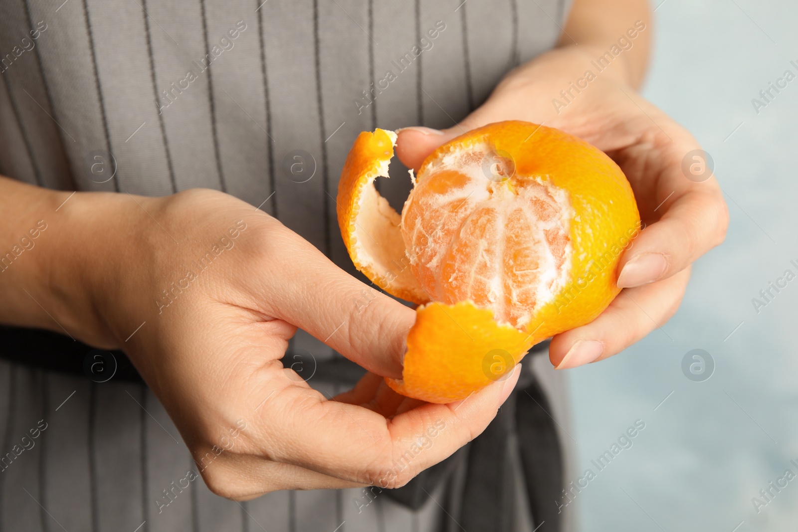 Photo of Woman peeling ripe tangerine, closeup. Citrus fruit