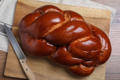 Photo of Homemade braided bread on wooden table, top view. Traditional Shabbat challah