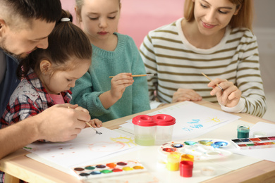 Photo of Lovely family painting at table indoors. Playing with children