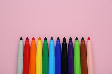 Photo of Many different colorful markers on light pink background, flat lay. Space for text