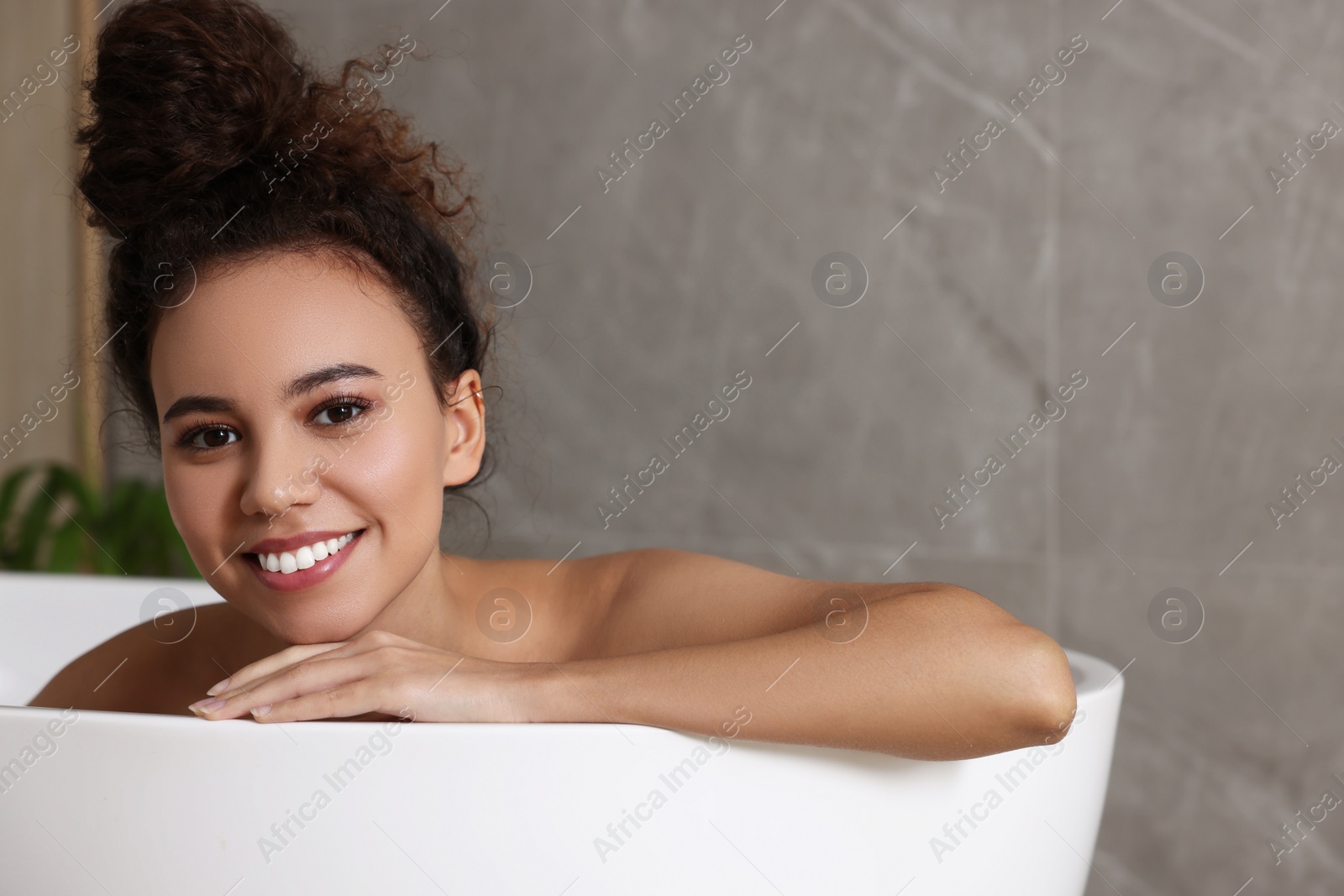 Photo of Beautiful African American woman taking bath indoors, space for text