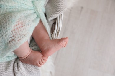 Photo of Newborn baby lying on plaid in basket, closeup of legs. Space for text