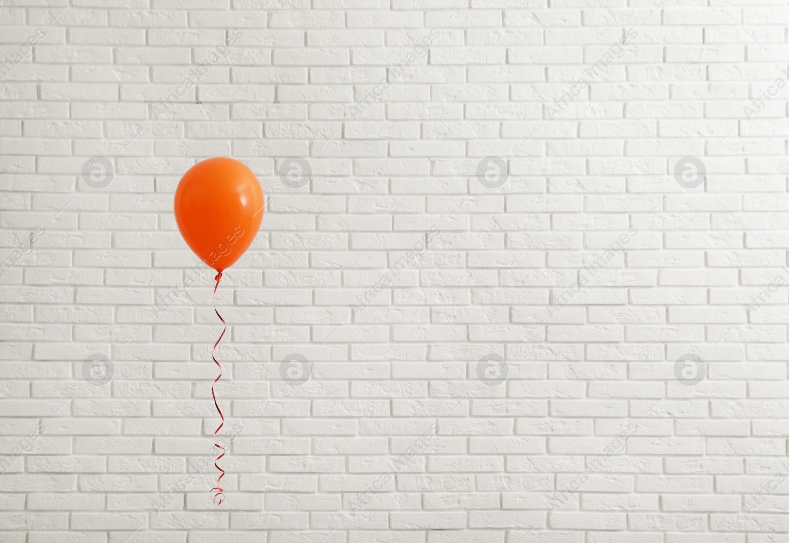 Photo of Bright balloon near brick wall, space for text. Celebration time