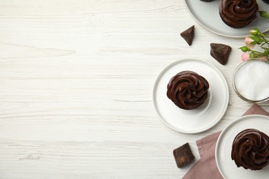 Flat lay composition with delicious chocolate cupcakes on white wooden table. Space for text