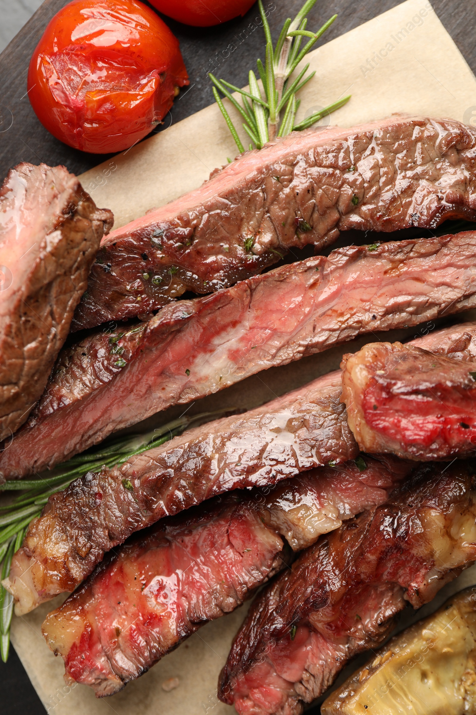 Photo of Delicious grilled beef with tomatoes and rosemary on table, top view