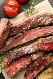 Photo of Delicious grilled beef with tomatoes and rosemary on table, top view