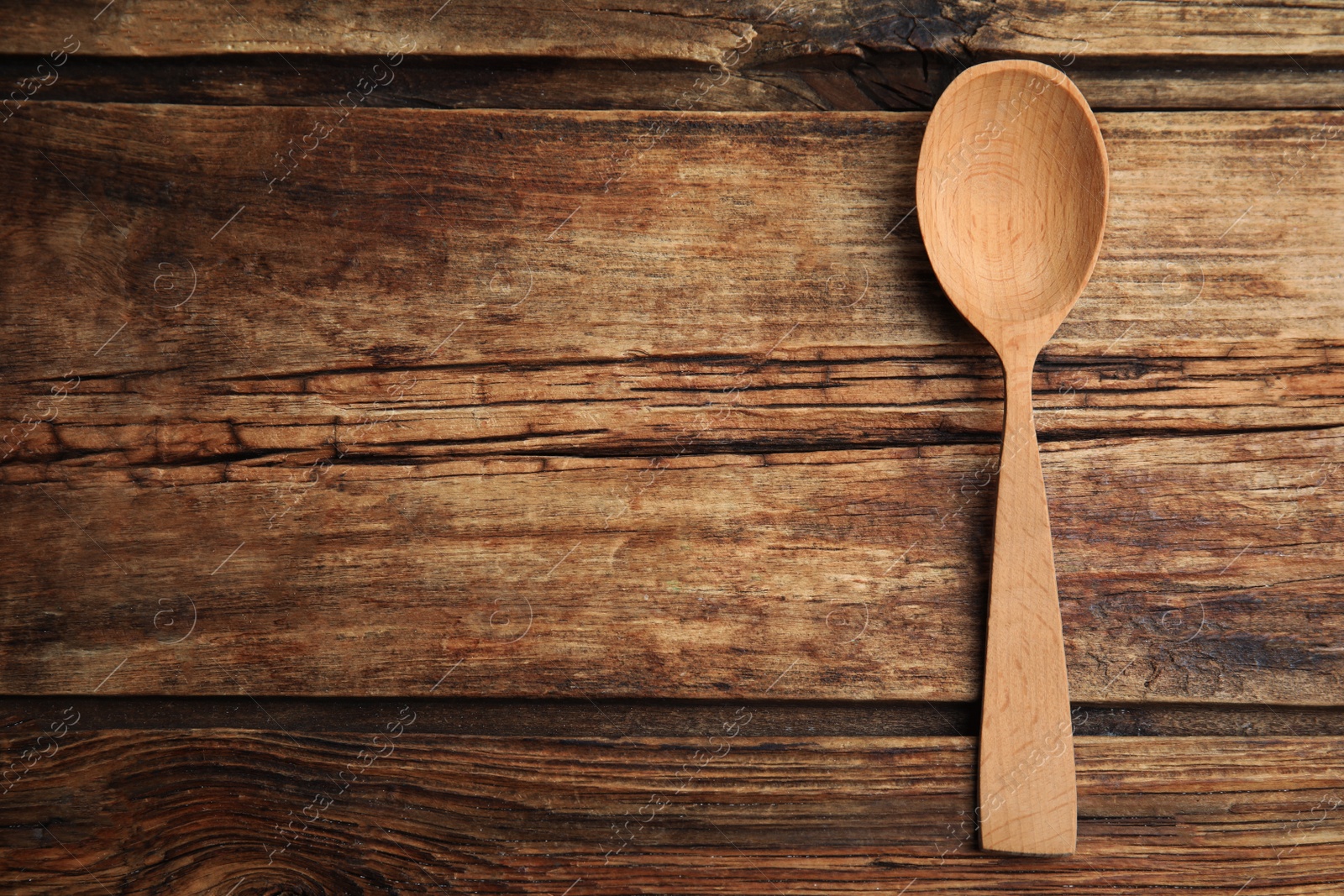 Photo of Handmade wooden spoon on rustic table, top view. Space for text