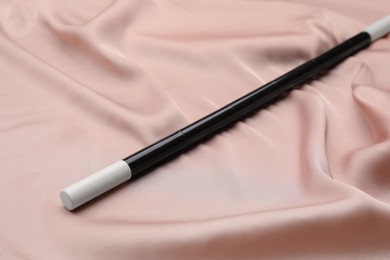 Photo of Beautiful black magic wand on pink fabric