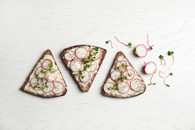 Tasty toasts with radishes, sprouts and chia seeds on white wooden background, top view