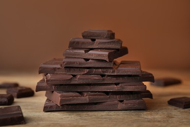 Photo of Pieces of tasty chocolate on wooden table, closeup