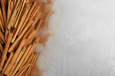 Photo of Aromatic cinnamon sticks and powder on grey table, flat lay. Space for text