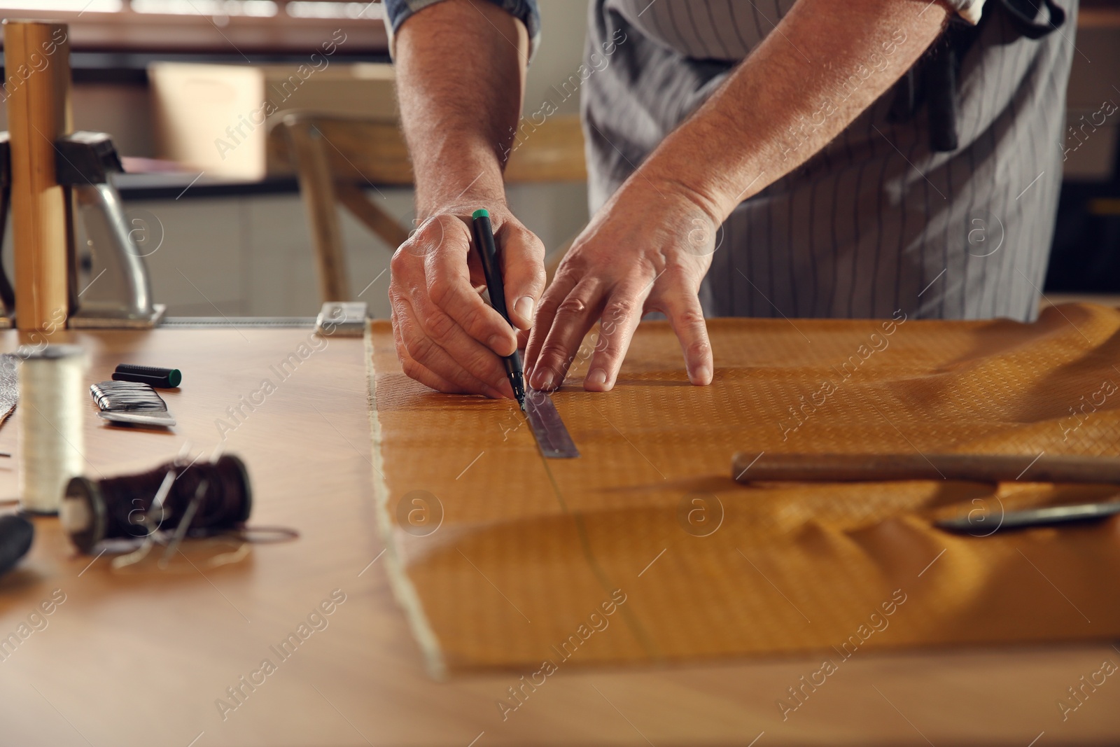 Photo of Man working with piece of leather in workshop, closeup