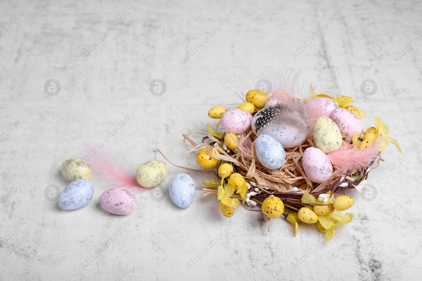 Photo of Decorative nest with many painted Easter eggs on light textured background