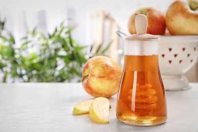 Photo of Jar of honey with dipper and apples on light table