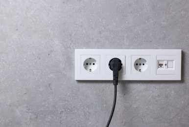 Photo of Power sockets and electric plug on grey wall, space for text