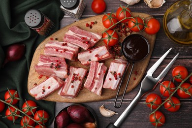 Flat lay composition with cut raw pork ribs and sauce on wooden table