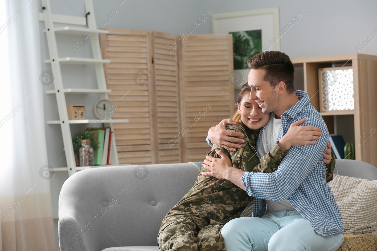 Photo of Woman in military uniform with her husband on sofa at home
