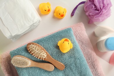 Towels, rubber ducks, hygrometer and baby care products on white table, flat lay