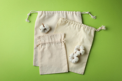 Photo of Cotton eco bags on light green background, flat lay