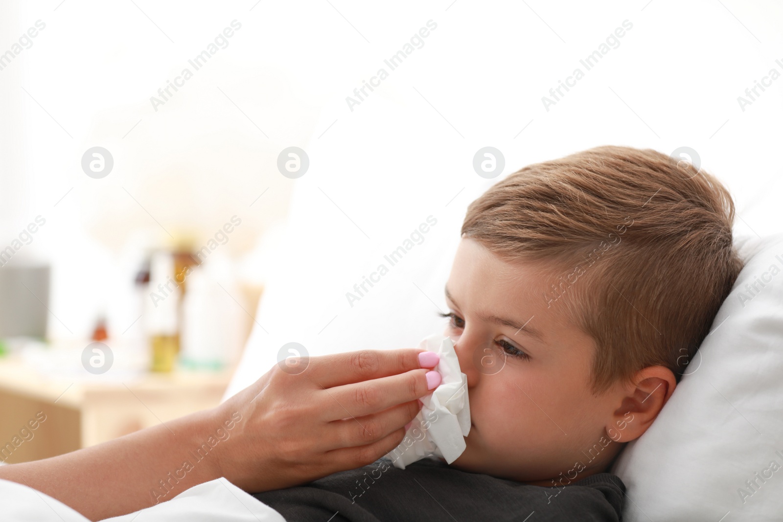 Photo of Mother taking care of little son suffering from cold in bed. Space for text