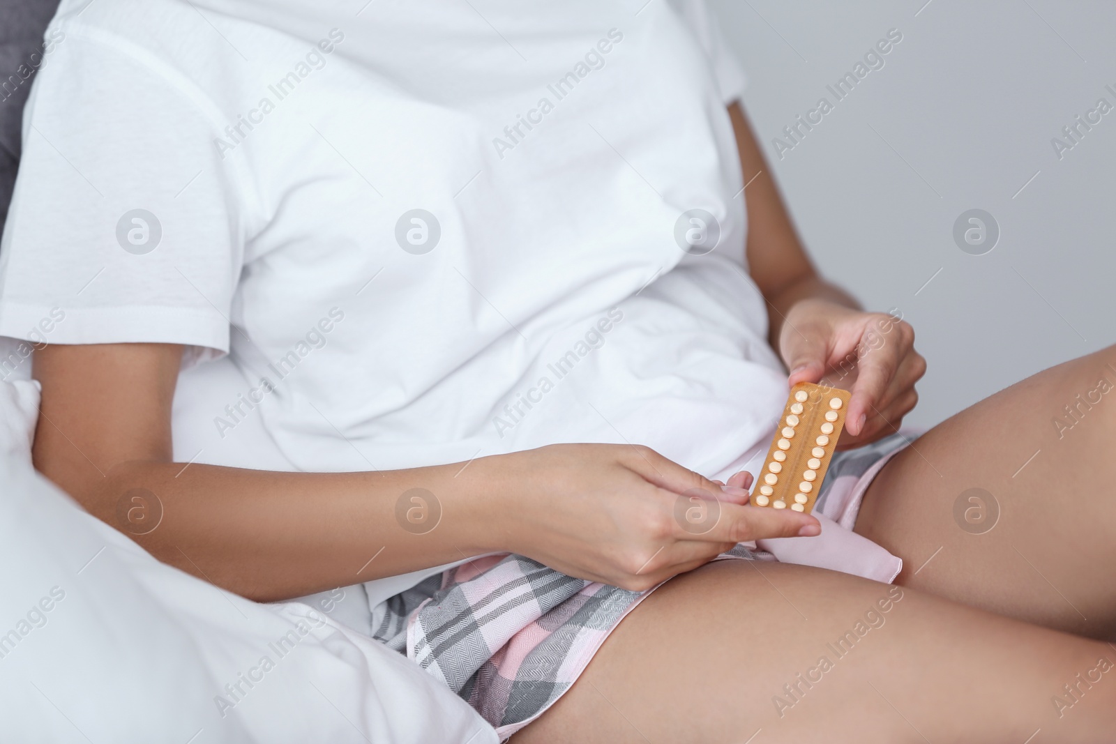 Photo of Young woman with birth control pills in bedroom. Gynecology
