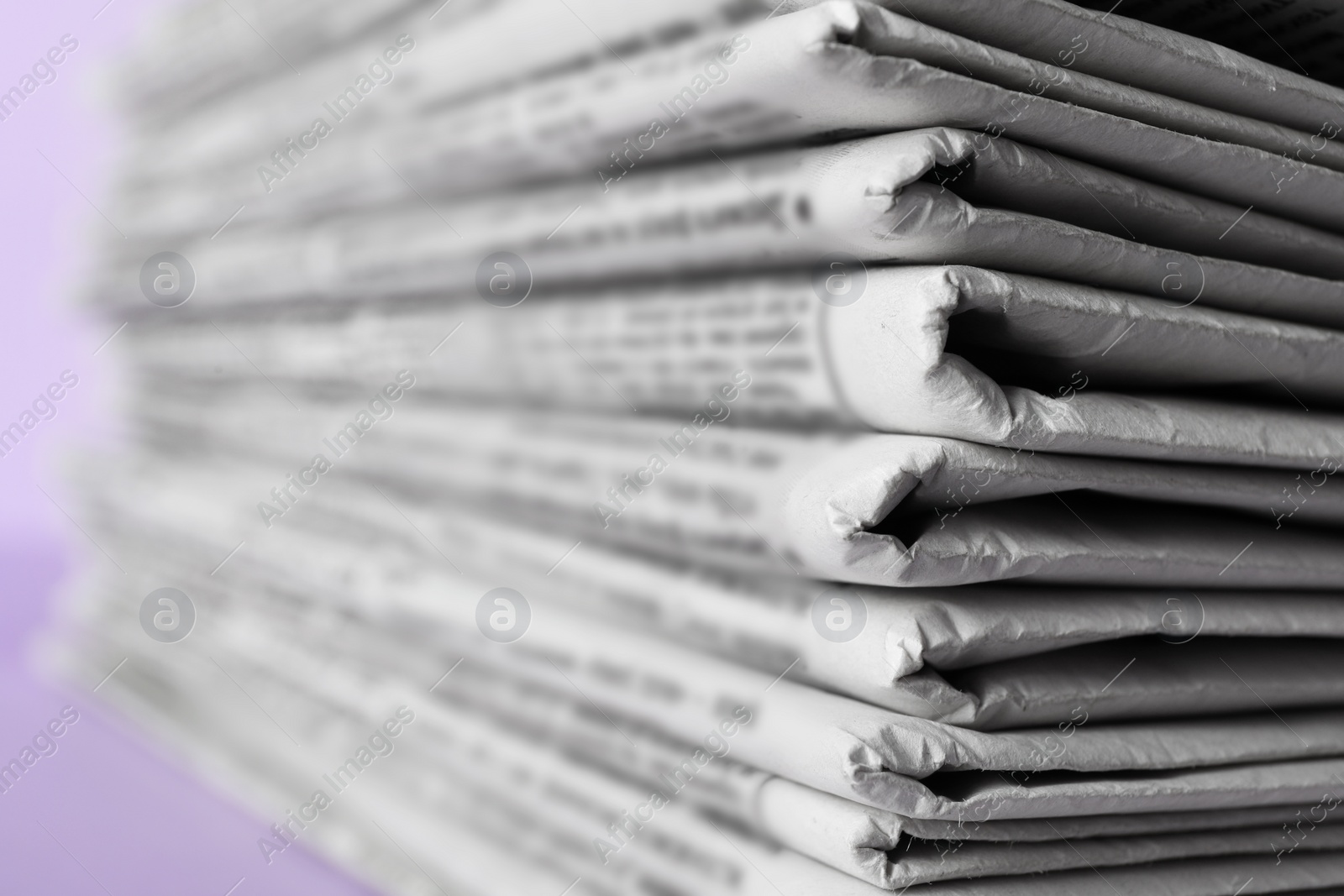 Photo of Stack of newspapers on light violet background, closeup. Journalist's work